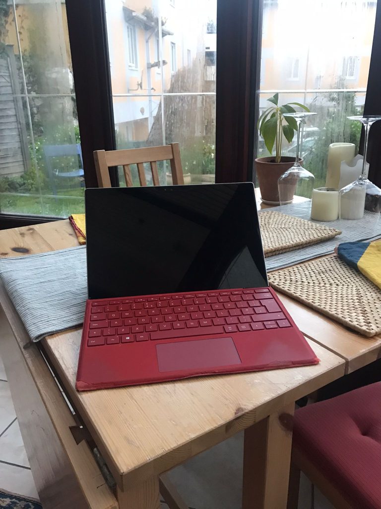Laptop with a red keyboard on a kitchen table.